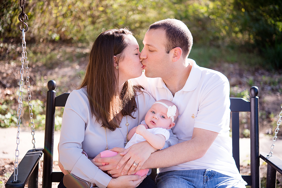 mommy kisses daddy with baby